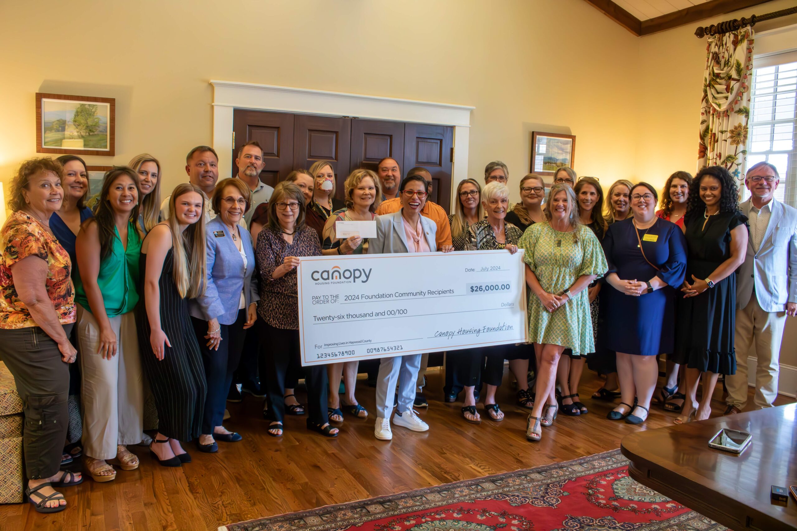 2024 Haywood Community Grants event with participants holding the big check of grants given totaling $26,000